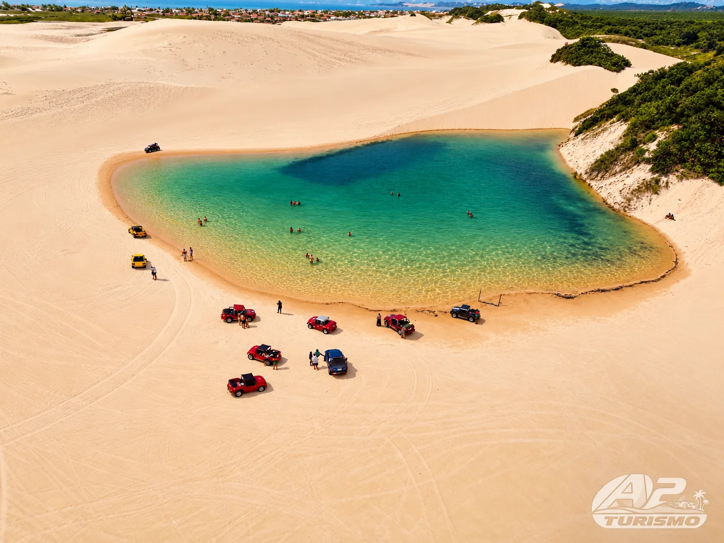 Pequena lagoa de águas verdes entre dunas, com buggys à margem